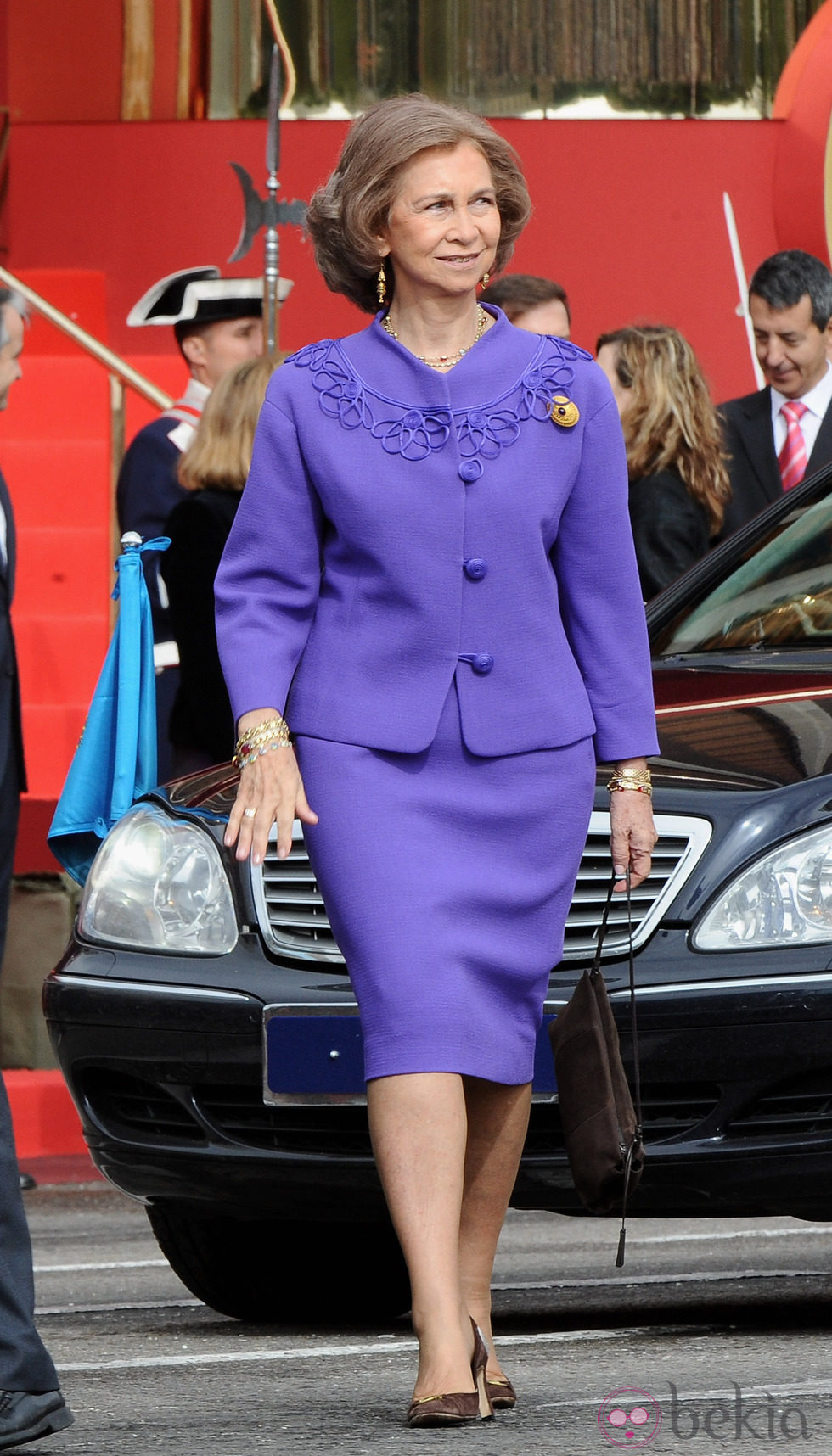 Look de la reina Sofía con vestido lady de color morado y detalles en relieve del mismo color