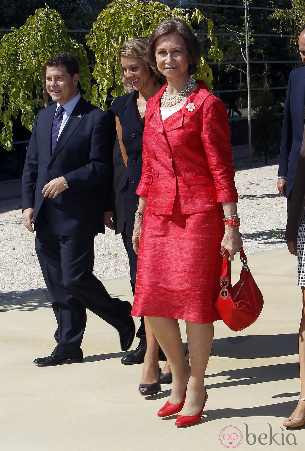 Look de la reina Sofía con vestido lady de color rojo, con textura en relieve y broche floral