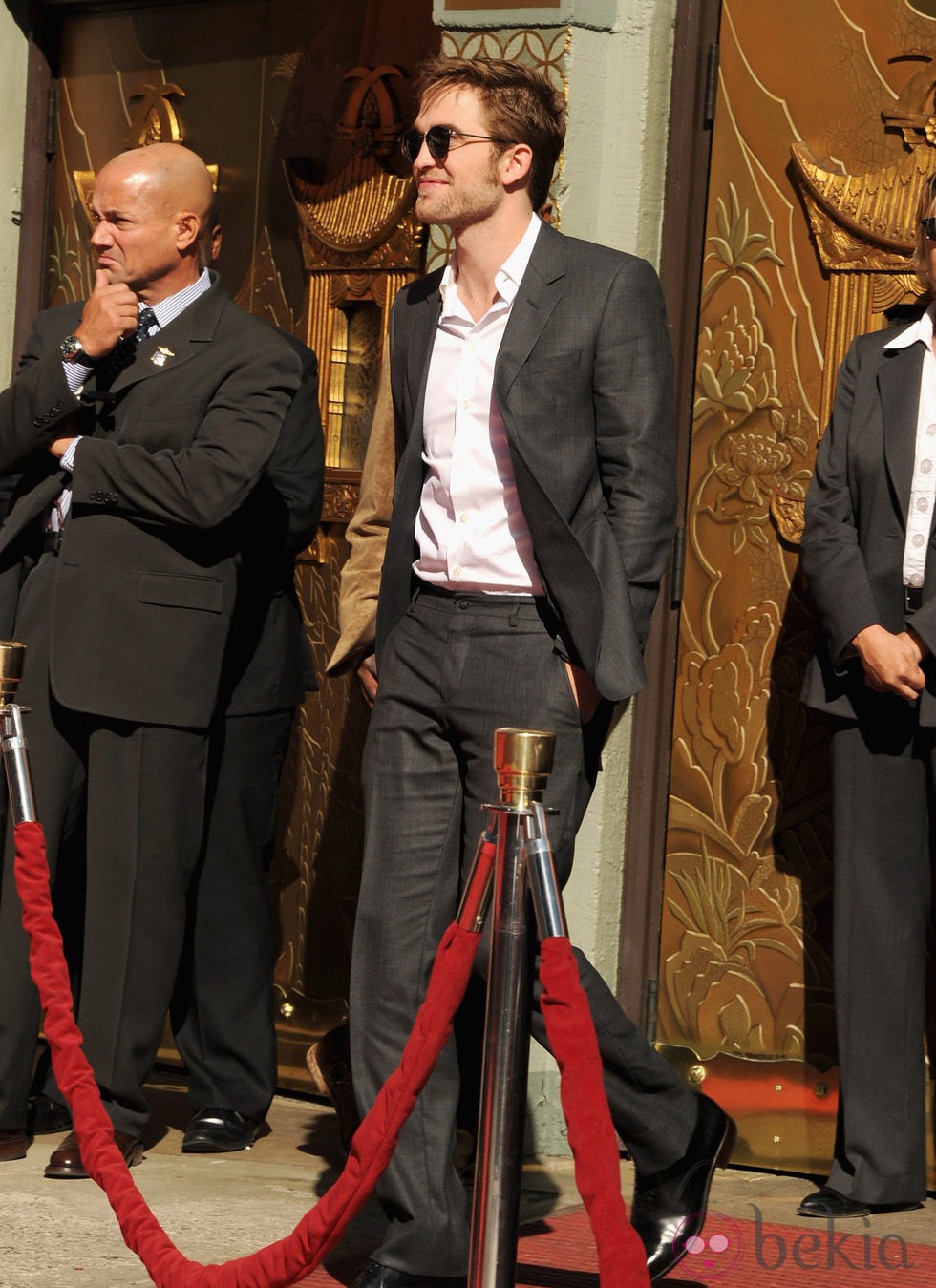 Robert Pattinson luciendo un traje gris oscuro y gafas de aviador