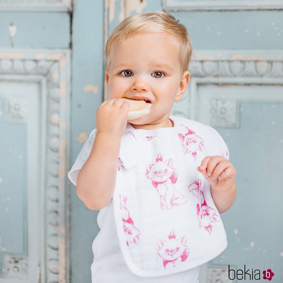 Bebé posando con un babero en color blanco con el estampado de Los Aristogatos de Disney para Aden+Anais 2018