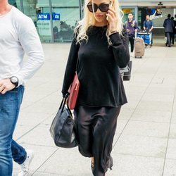 Rita Ora con look 'total black' de vestido satinado en el aeropuerto de Heathrow