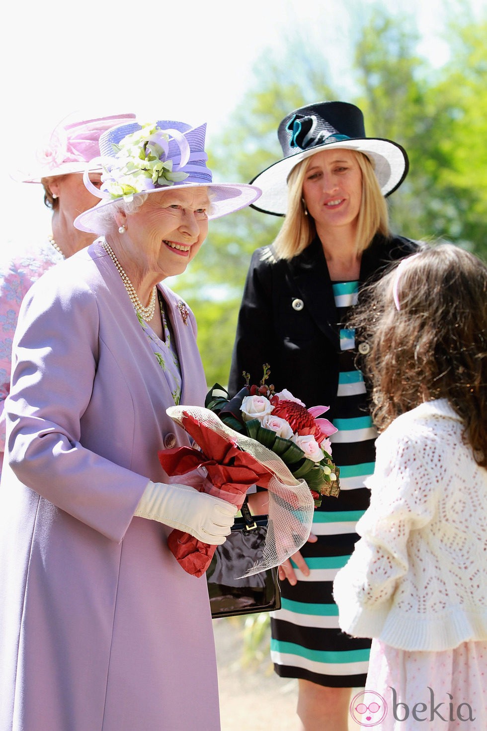 La Reina Isabel II con un conjunto violeta y sombrero en el mismo color