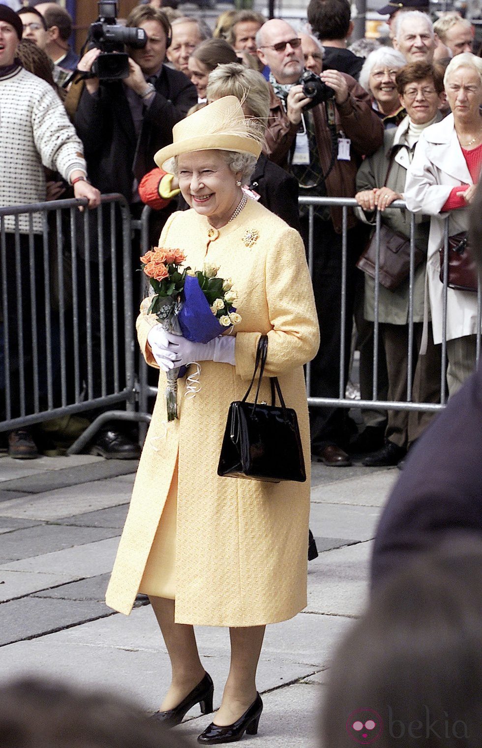 La Reina Isabel II de Inglaterra con un vestido primaveral en color amarillo de Angela Kelly