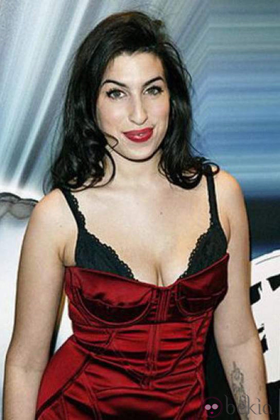 Amy Winehouse deja asomar su sujetador con un ajustado vestido rojo