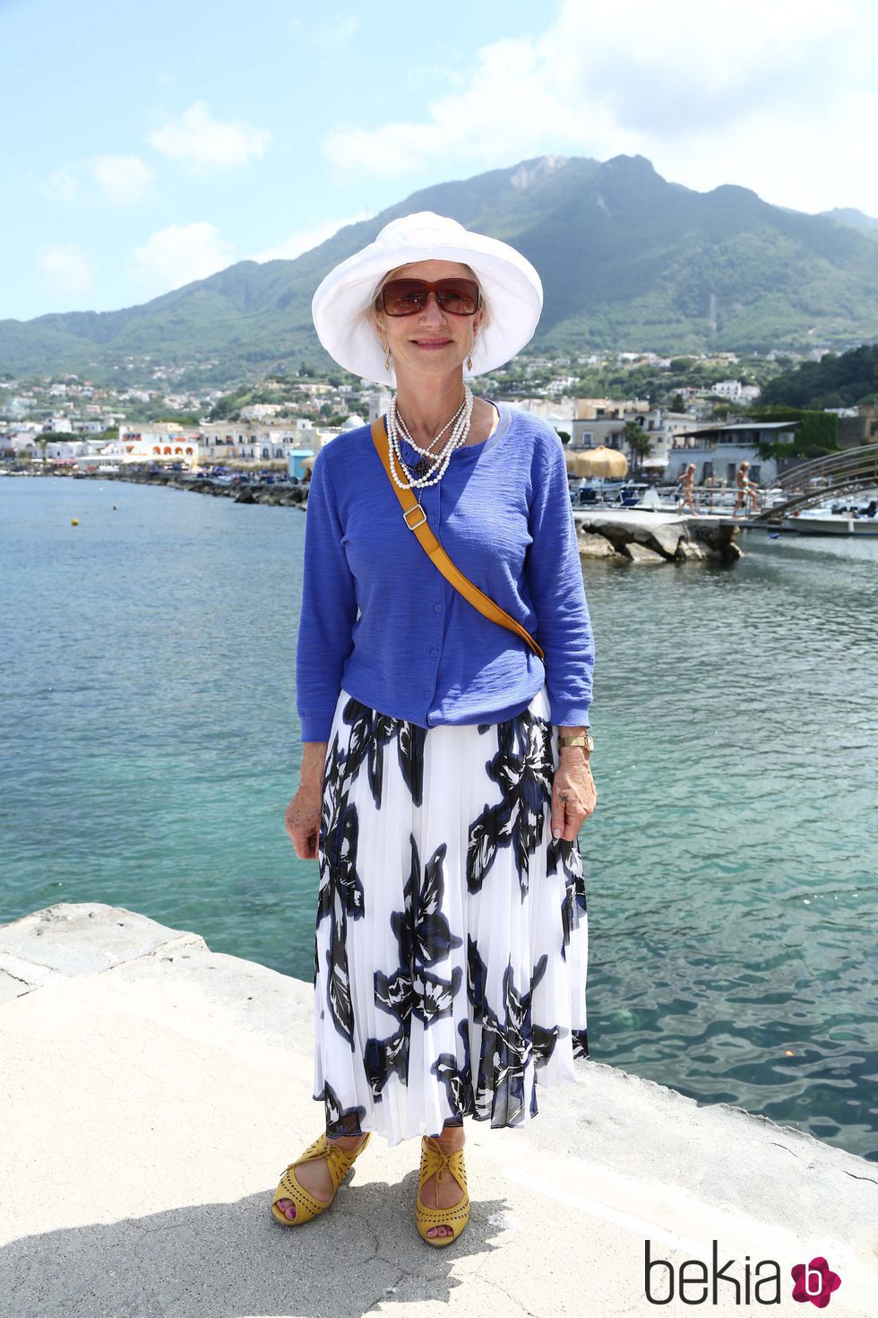 Helen Mirren con pamela blanca, chaqueta azul y falda estampada