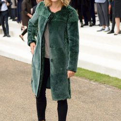 Sienna Miller con abrigo verde y pantalón pitillo negro en el desfile de Burberry en la London Fashion Week