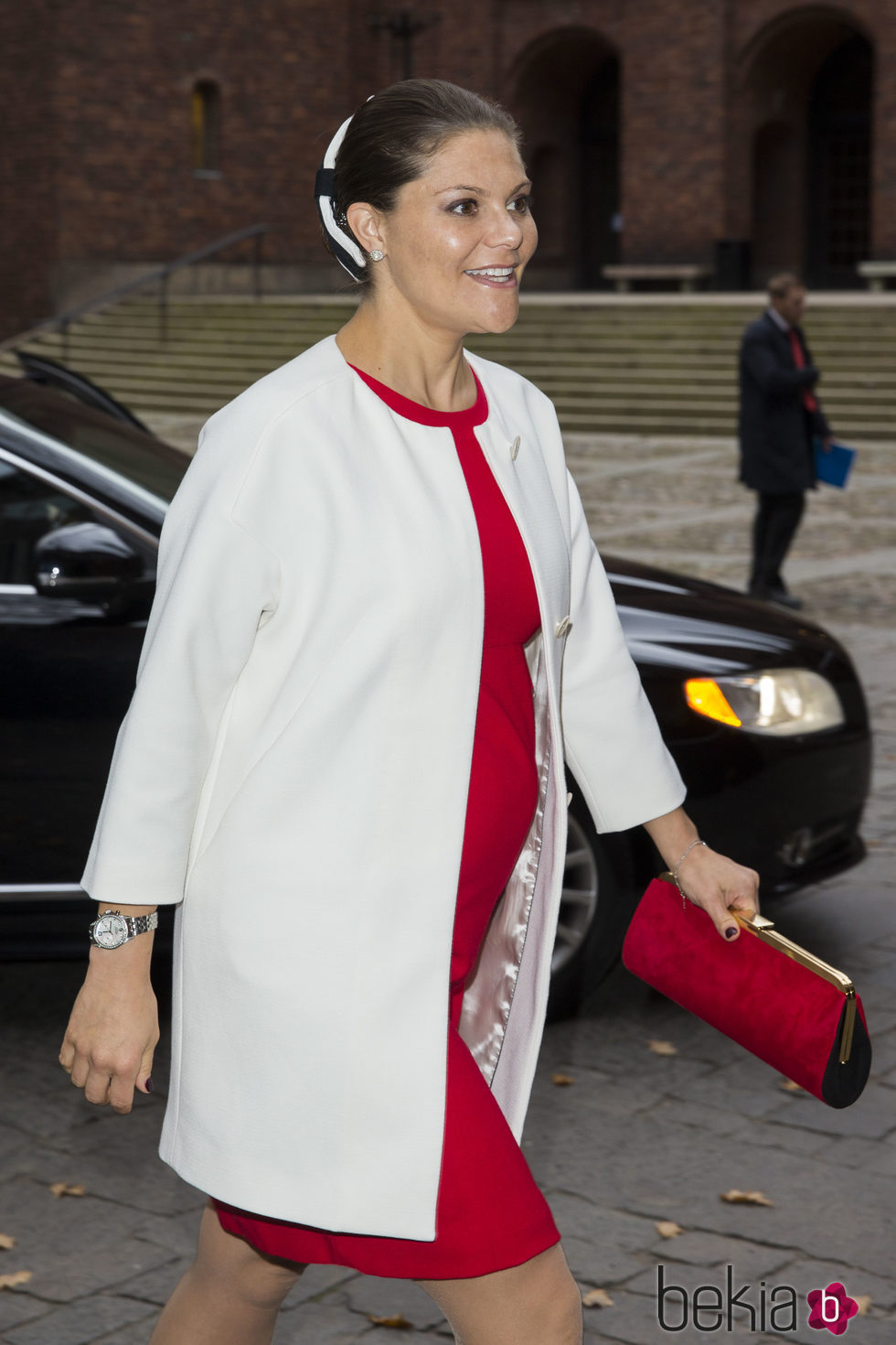 La Princesa Victoria de Suecia con un vestido rojo y un abrigo blanco en un acto en Estocolmo