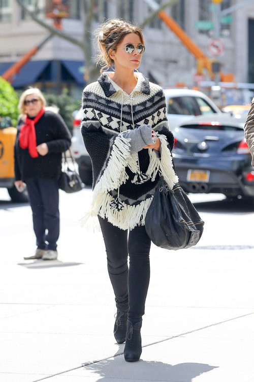 Kate Beckinsale con poncho tejido, pantalón y botines negros